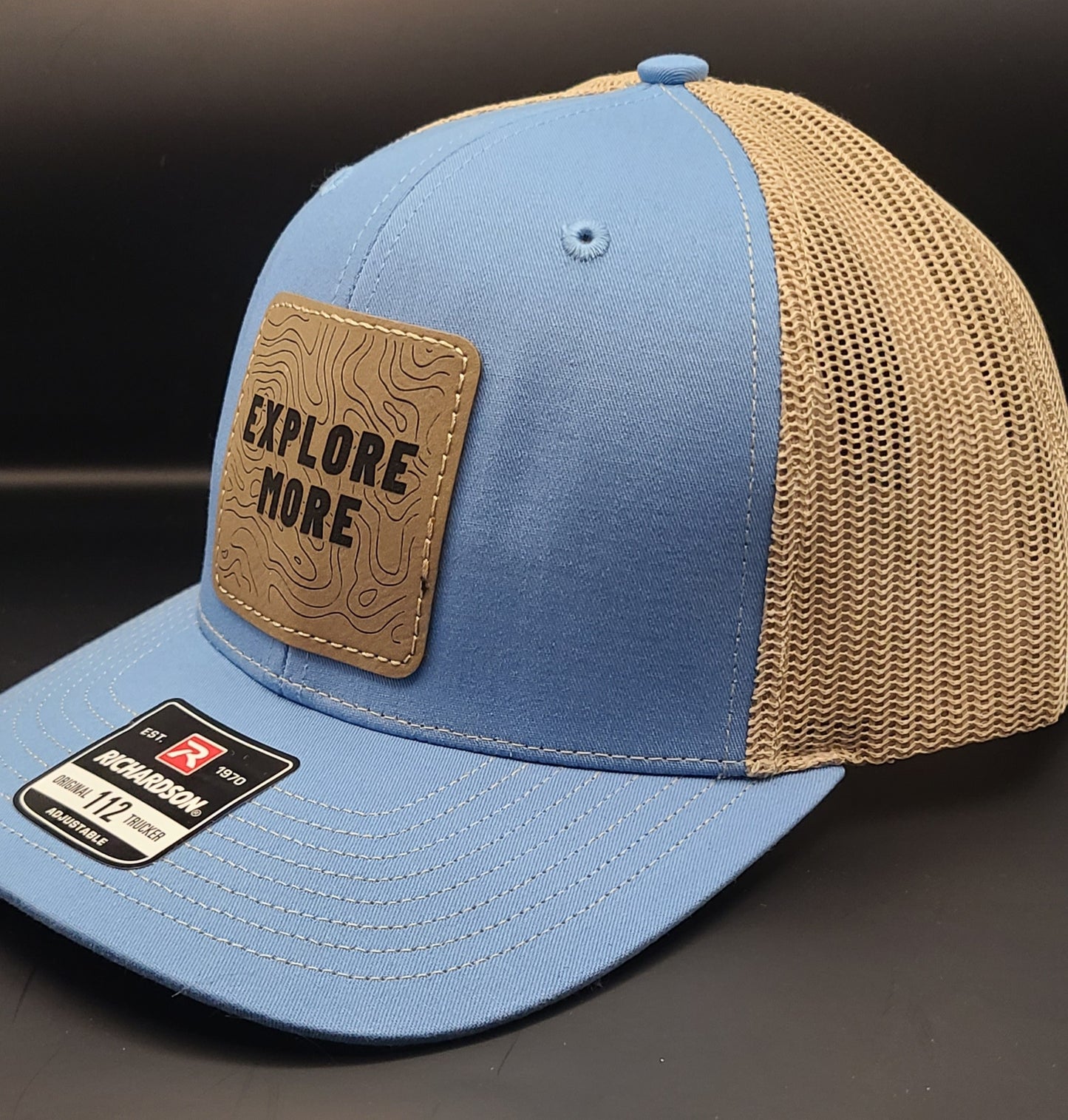 TRUCKER HAT WITH SQUARE PATCH THAT SAYS "EXPLORE MORE" (COLUMBIA BLUE/KHAKI)